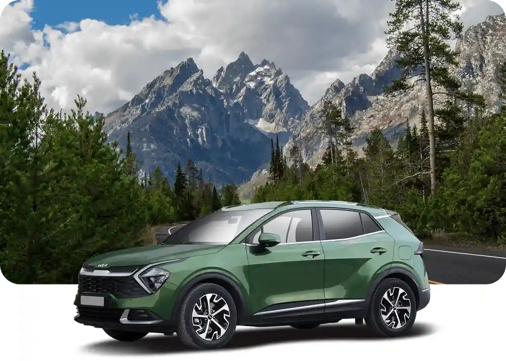 Green car in front of a mountain landscape